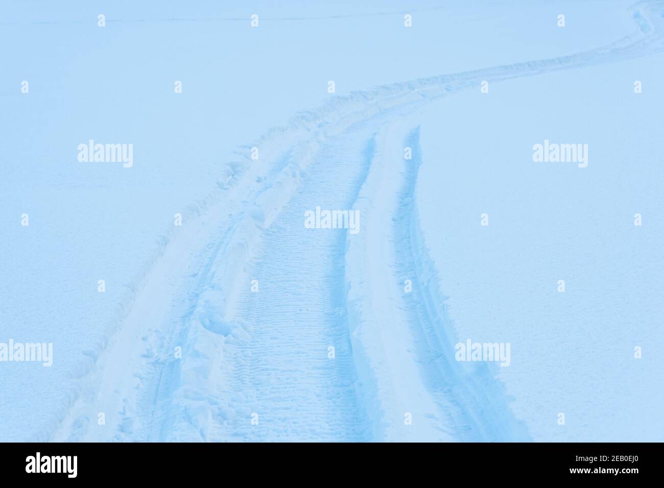 Snowmobile tracks in deep snow. Twisting traces of a snowmobile crossing snow covered field Stock Photo