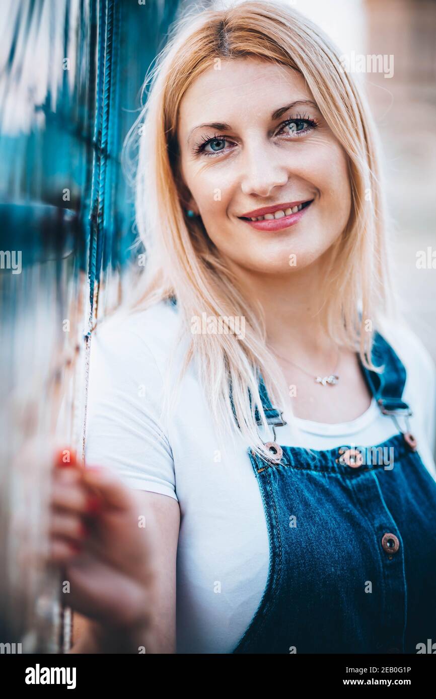 Portrait of a blue-eyed blonde woman in jeans with suspenders Stock Photo
