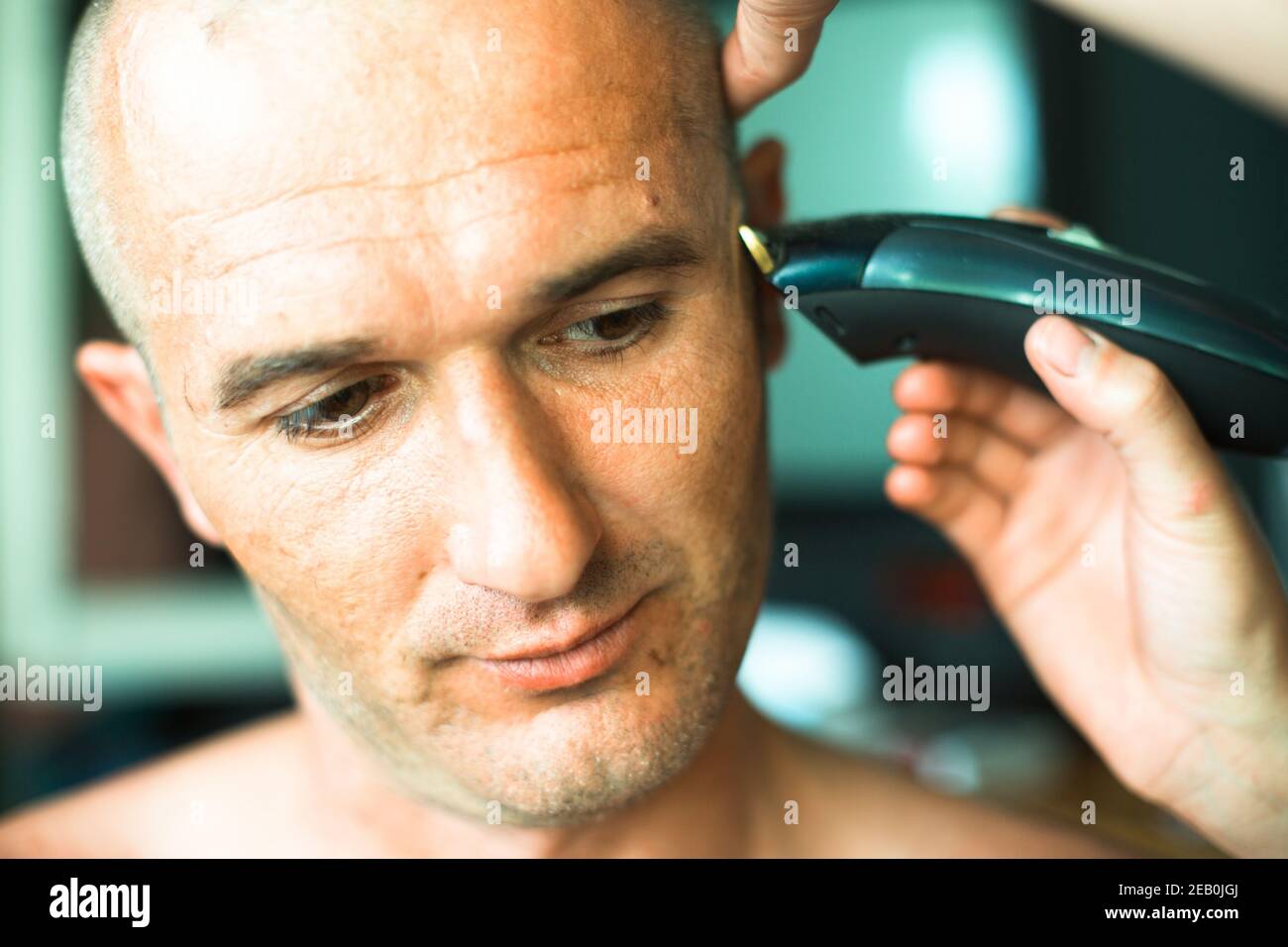 Hairdresser shaving man with hair trimmer. Close-up. Stock Photo