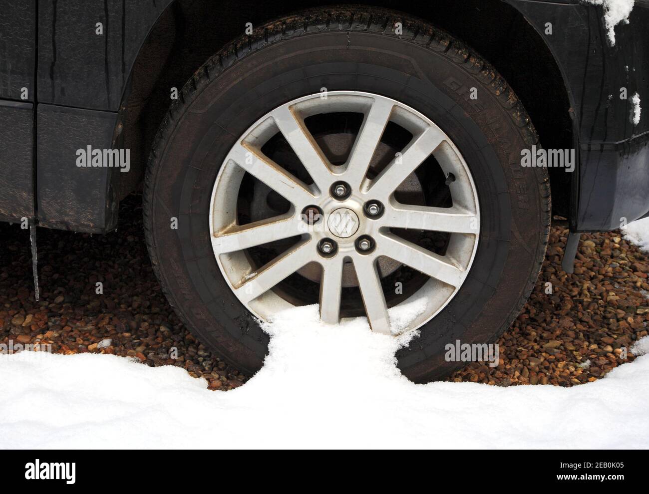The front offside wheel of a Suzuki Grand Vitara XEC parked in winter conditions with snow and icicle hanging from bodywork. Stock Photo