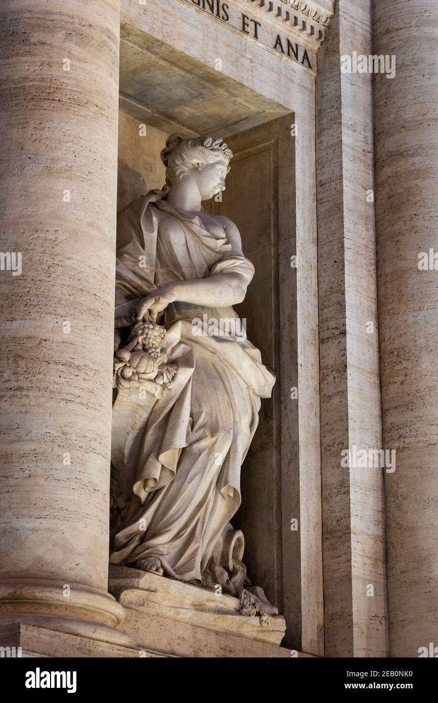 Statue of Abundance holding a horn of plenty in niche of the Trevi Fountain at night in Rome, Italy Stock Photo