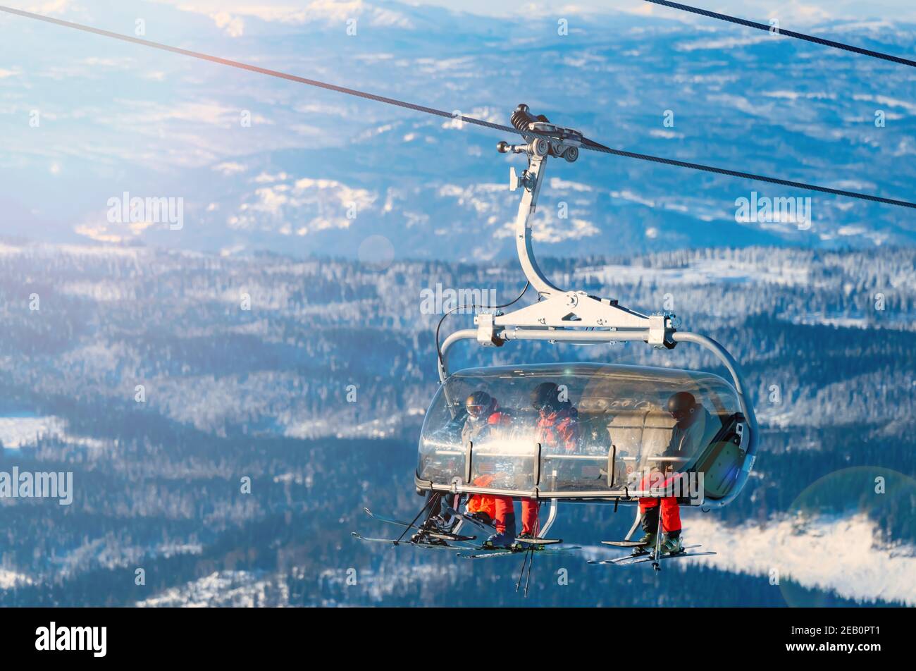 Group of skiers riding a ski lift to the top of a mountain at a ski ...