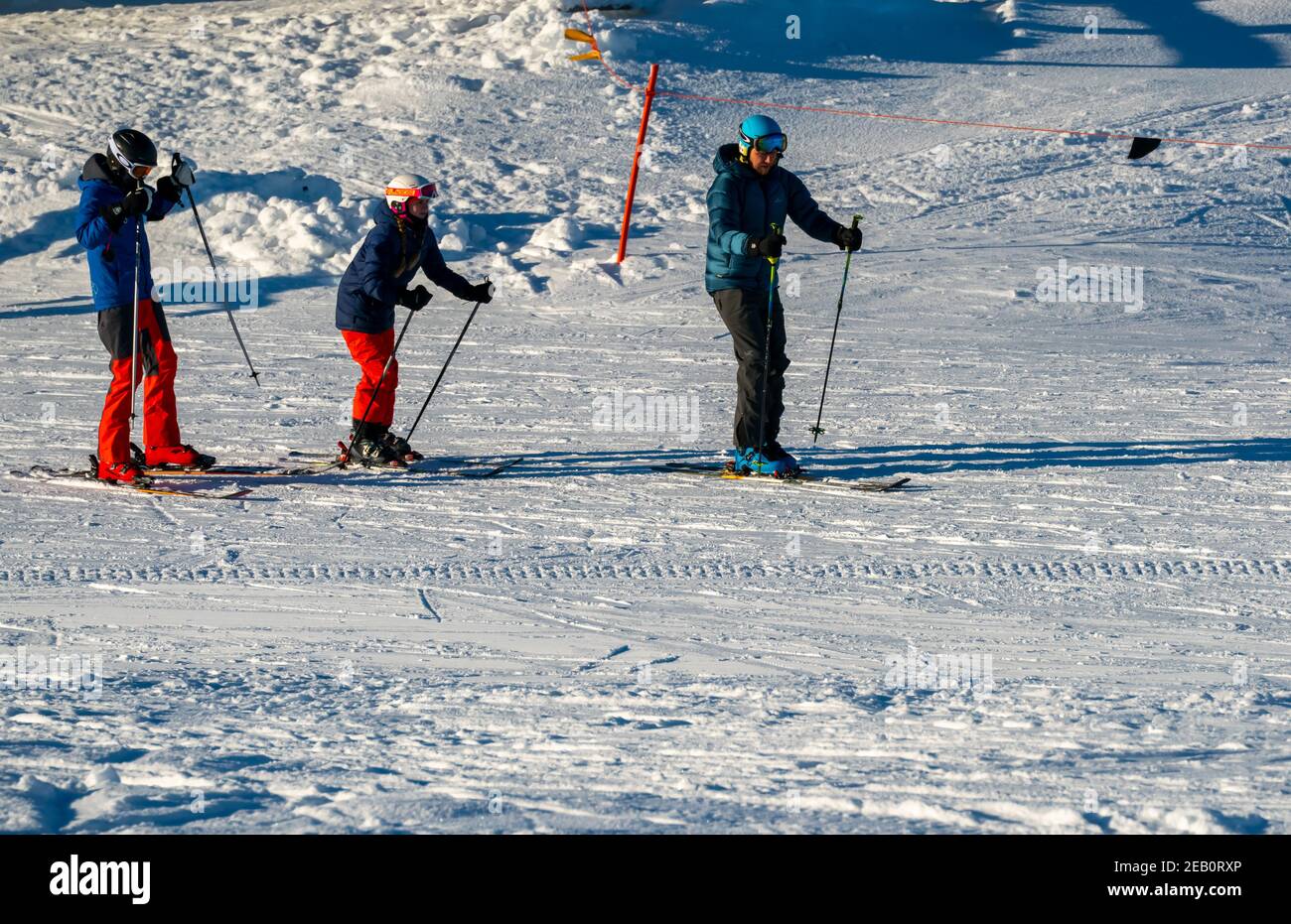 Family skiing down a slope at a alpine ski resort. Stock Photo