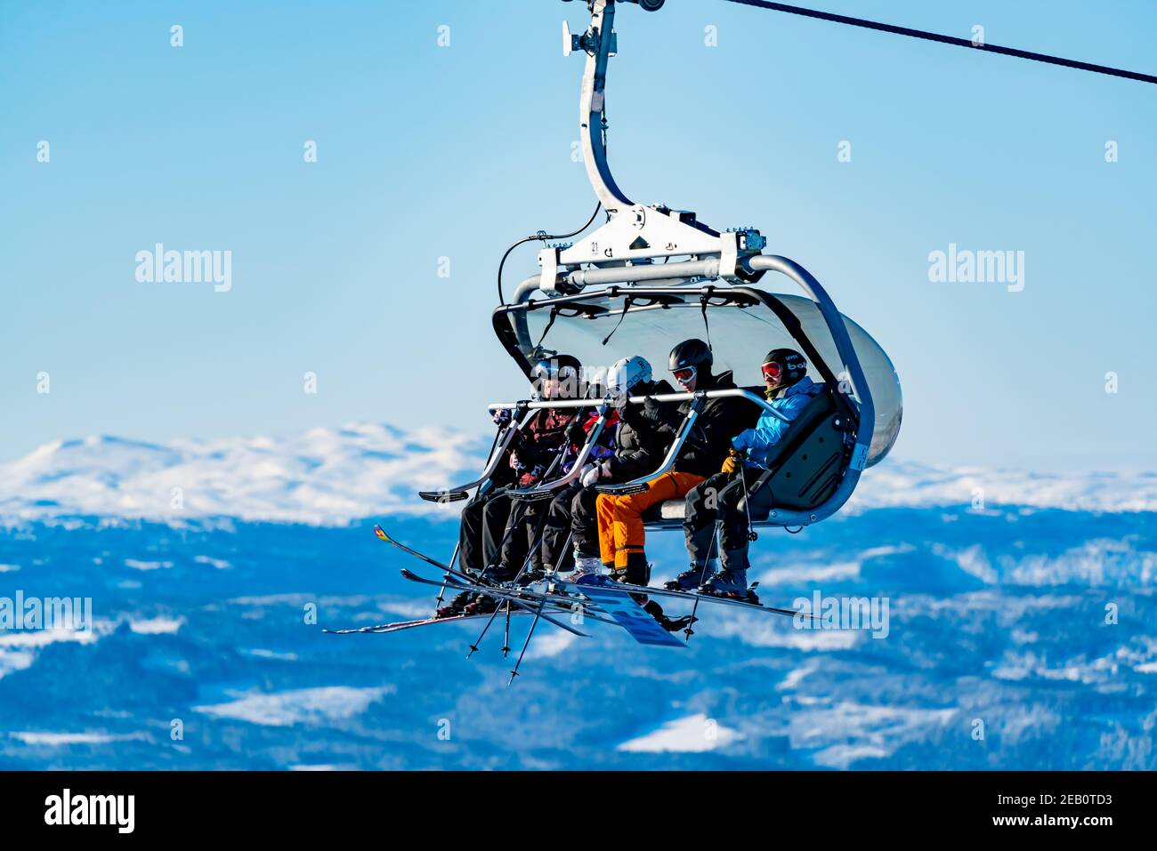 Group of skiers riding a ski lift to the top of a mountain at a ski resort. Stock Photo