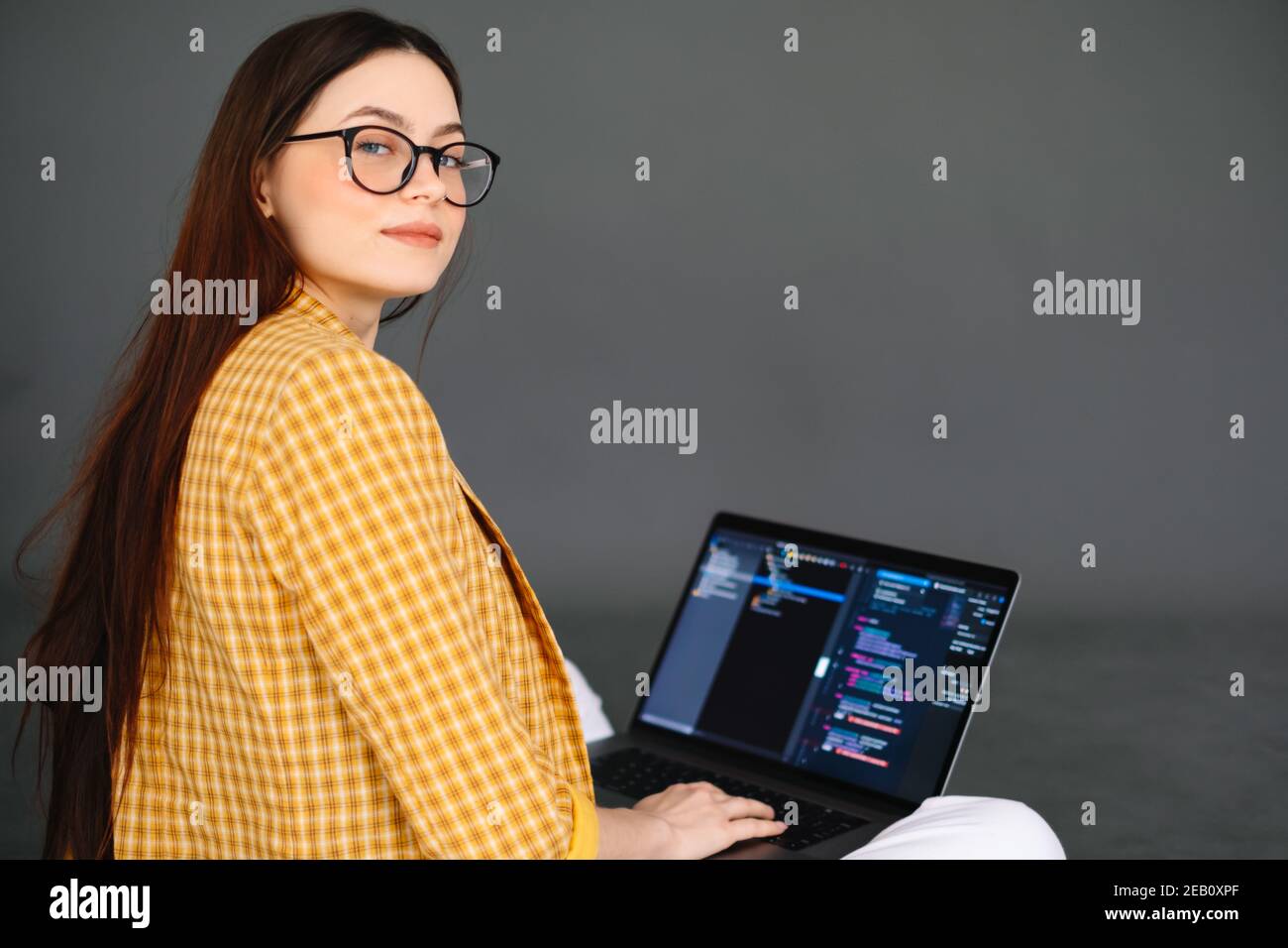 Portrait of young woman mobile developer with laptop, writes program code on a computer, programmer work. Stock Photo