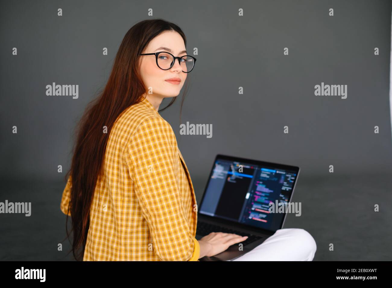 Portrait of young woman mobile developer with laptop, writes program code on a computer, programmer work. Stock Photo