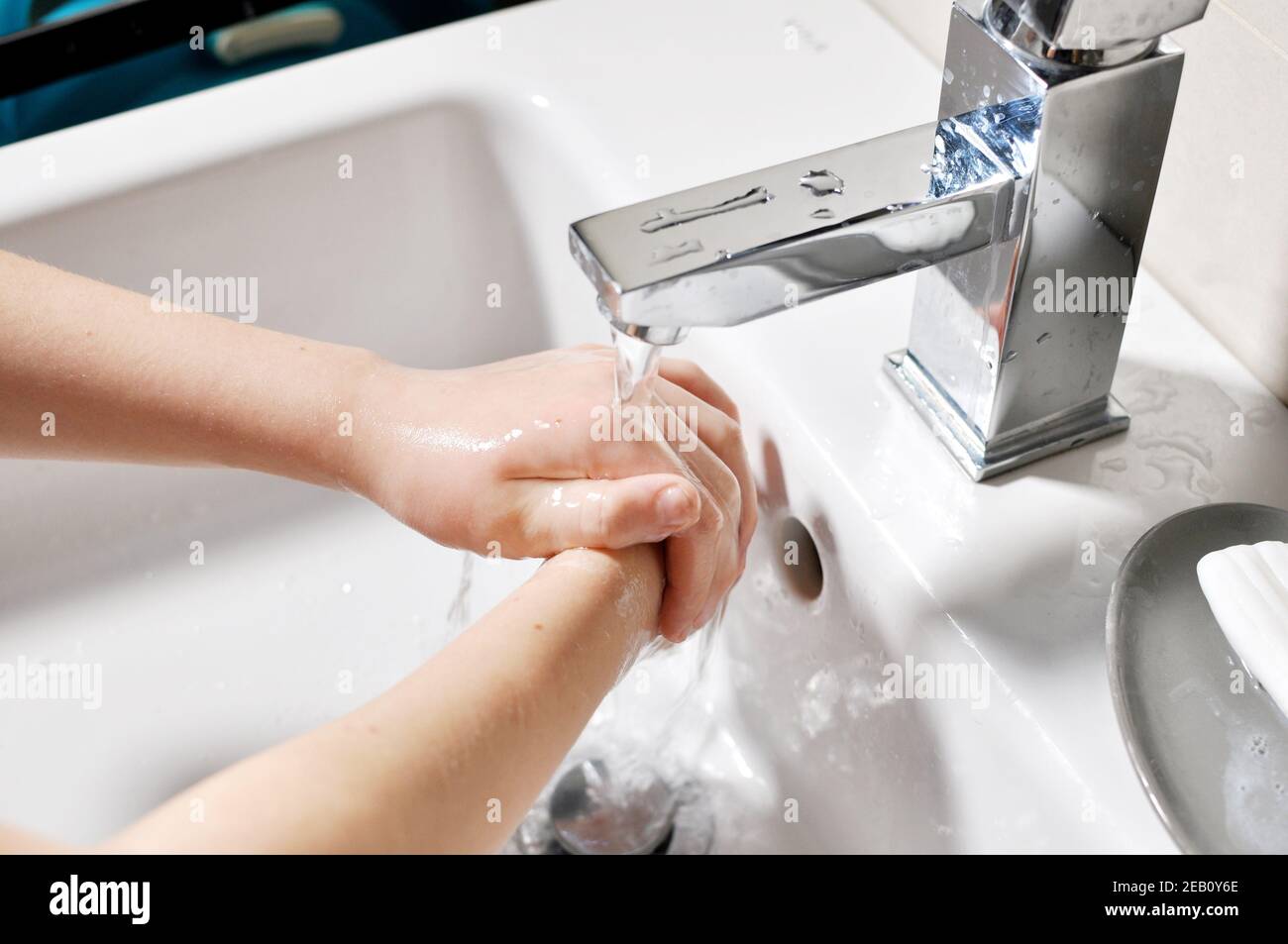 White European girl (child, kid) washing hands under the running water over the sink Stock Photo