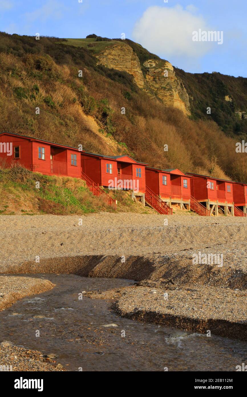 Red beach huts in village of Branscombe, Devon on the Jurassic Coast Stock Photo