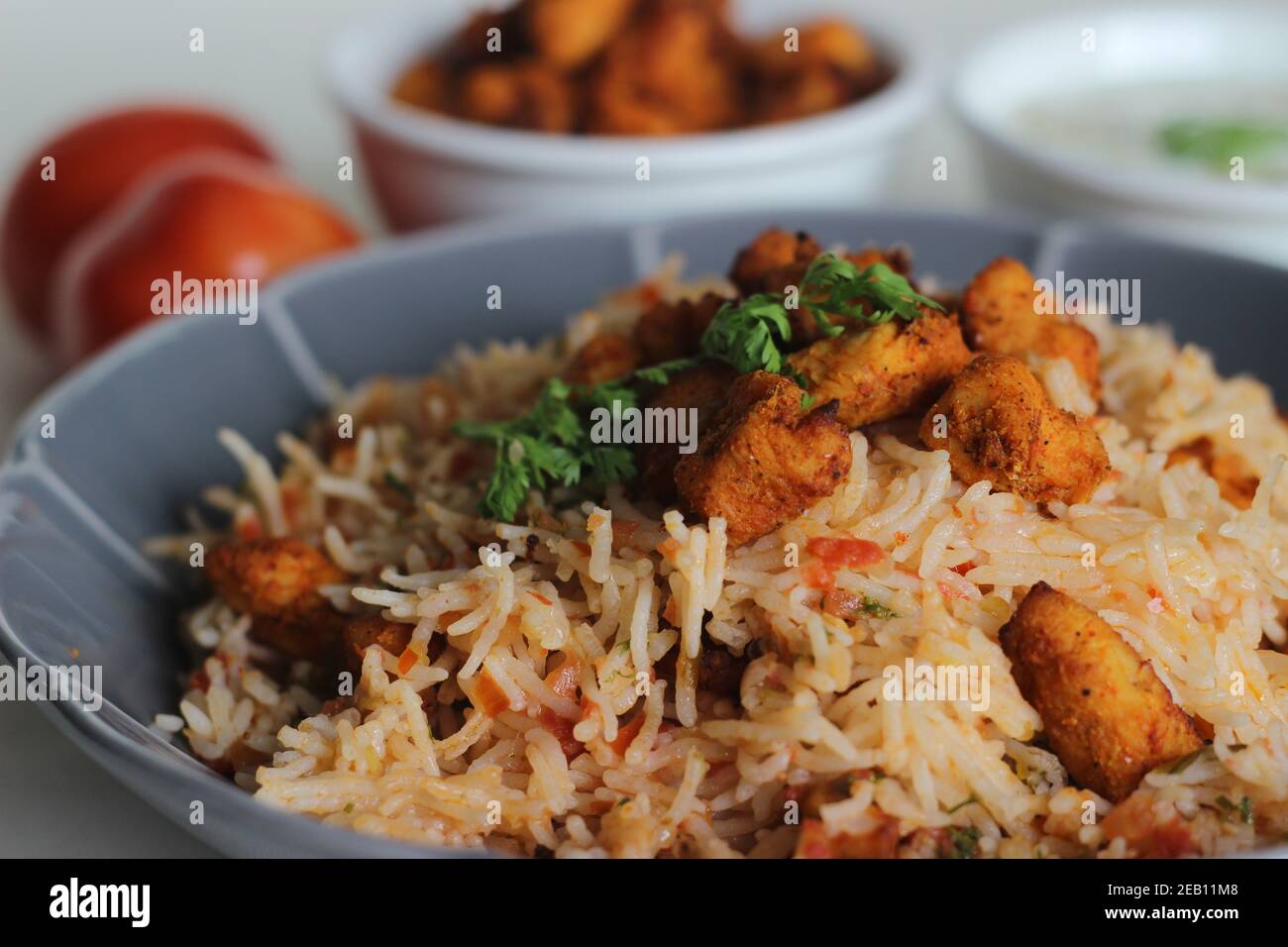 Tomato rice served with raita and air fried boneless chicken bites ...