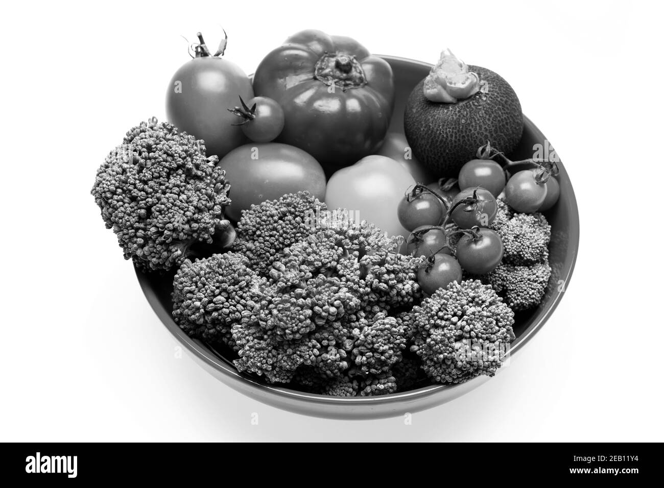 Set of salad ingredients isolated on white background. Cuisine and vegan diet concept. Composition of vegetables in red bowl. Broccoli, tomatoes, cherry tomatoes, black radish and peppers on plate. Stock Photo