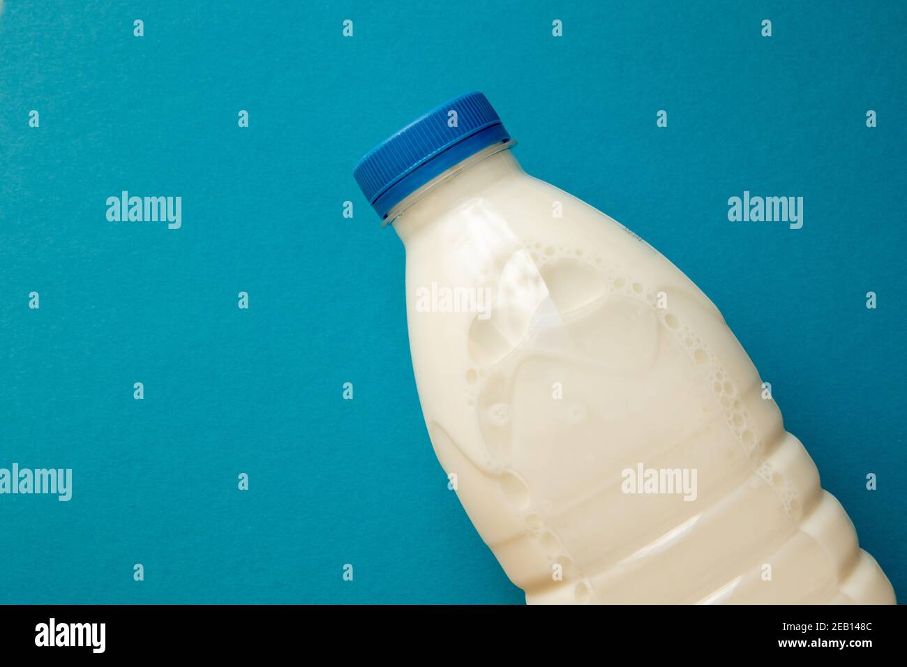 Fresh dairy product in full plastic bottle for milk, kefir or yoghurt with blue cap in center of blue background. Top view. Stock Photo