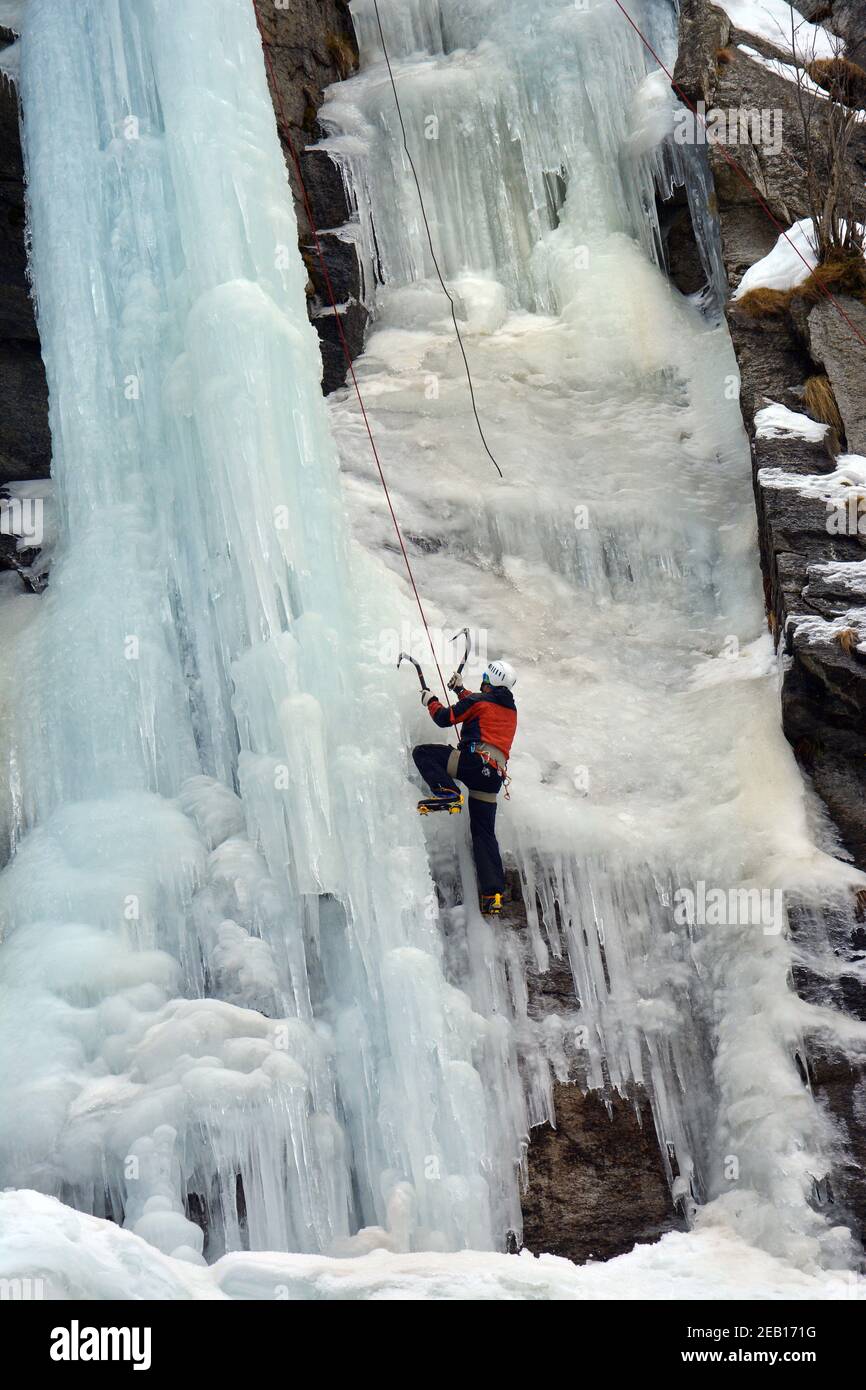 Mountaineer climbs an icefall in Alps of Piedmont, Italy. Stock Photo