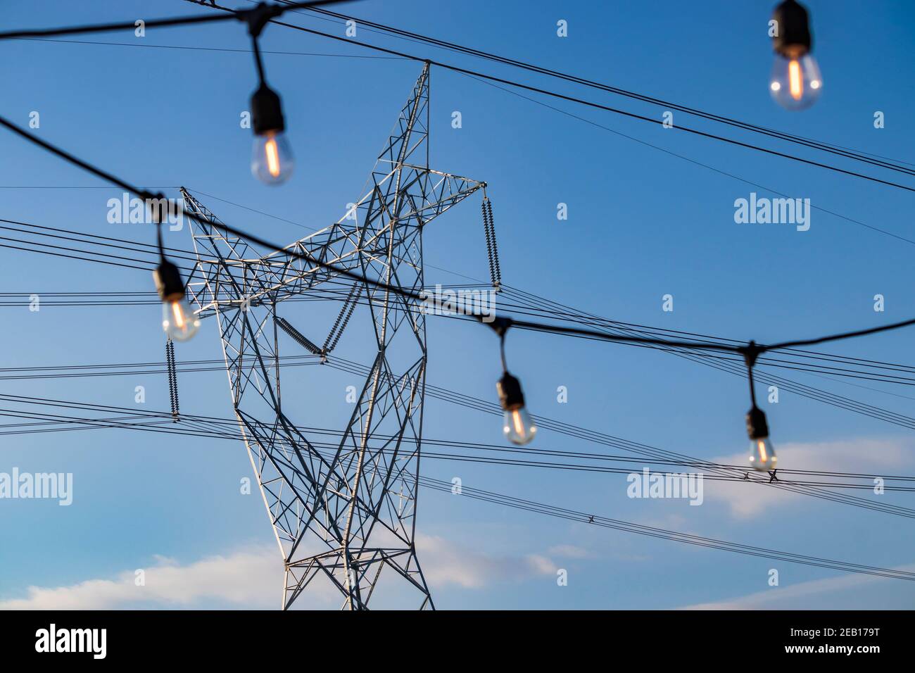 Edison style string lights and electric pylon in the background on a sunny day Stock Photo