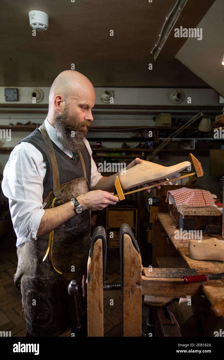 Fitter and Last Maker works at his bench inside John Lobb, makers of the finest hand made bespoke shoes and boots, Mayfair, London, England, UK Stock Photo