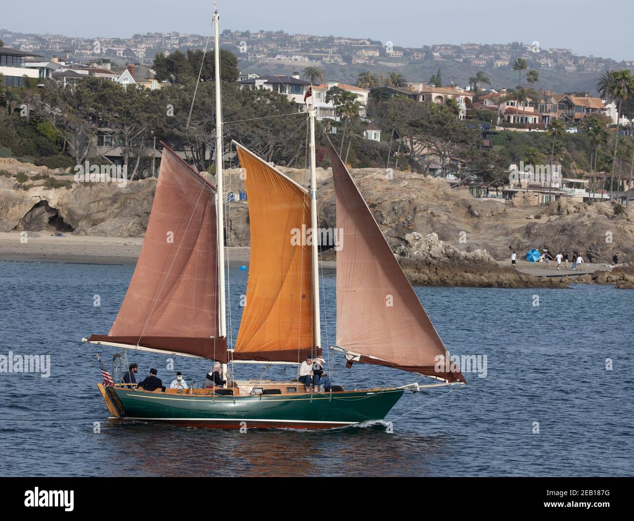 Traditional sailing boat leaving harbour at Newport Beach with waterside houses California USA Stock Photo