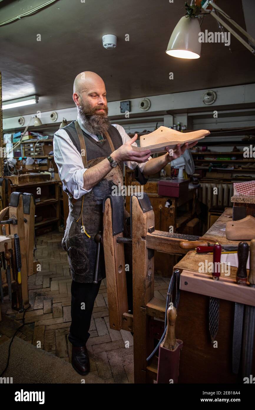 Fitter and Last Maker works at his bench inside John Lobb, makers of the finest hand made bespoke shoes and boots, Mayfair, London, England, UK Stock Photo