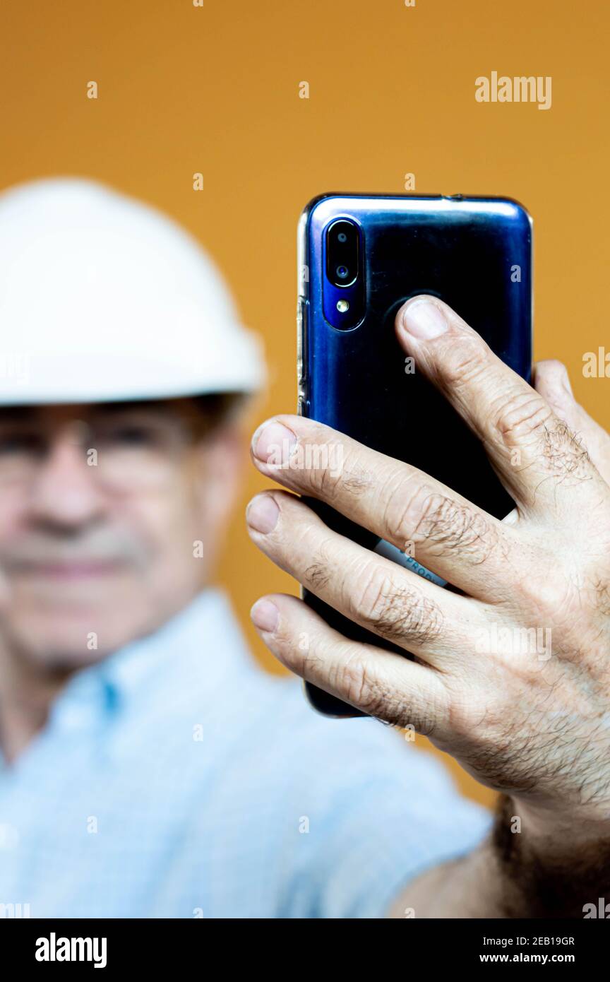White man in a white engineer helmet holding a mobile. Stock Photo