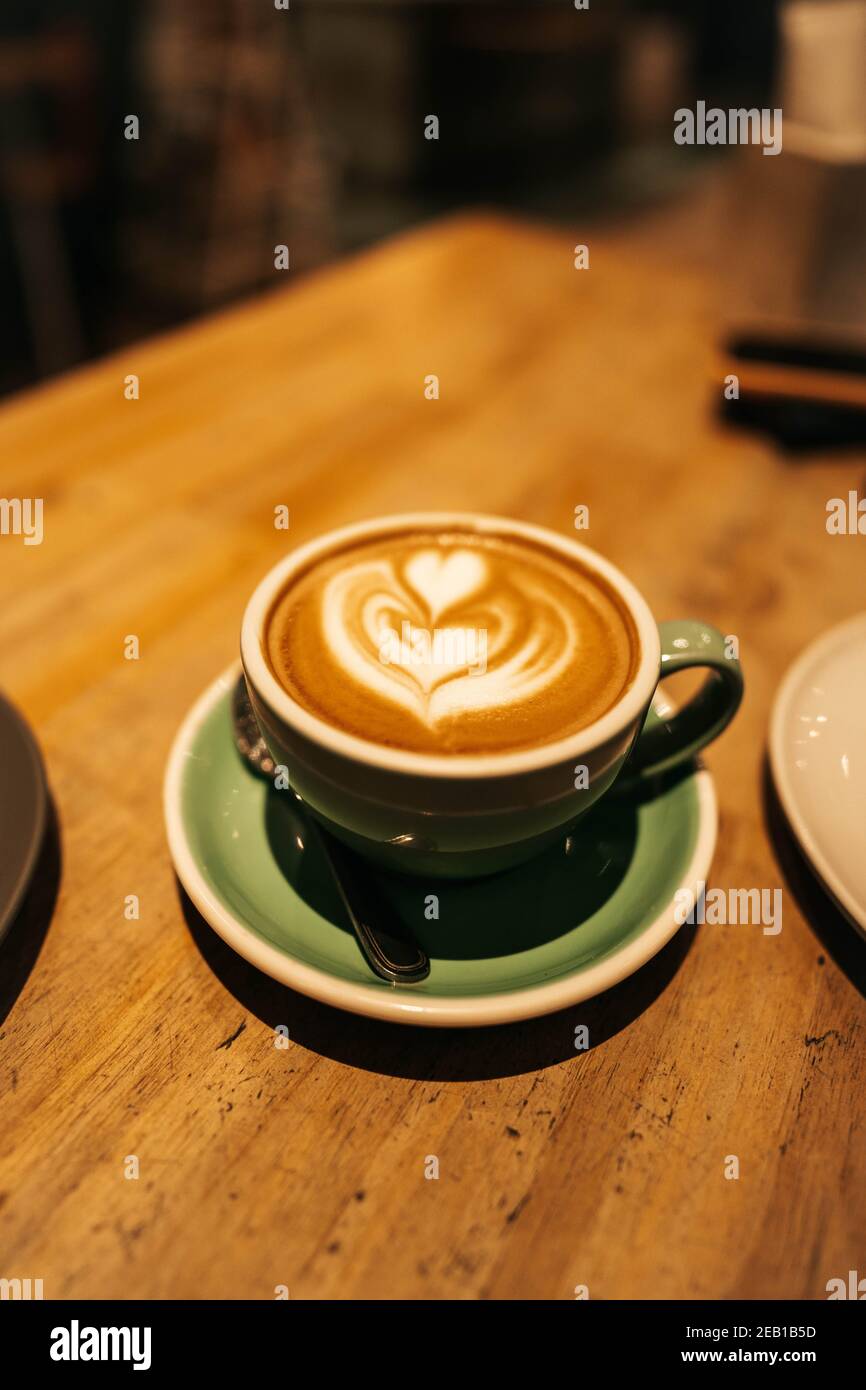 coffee latte art in green ceramic cup on wood background Stock Photo