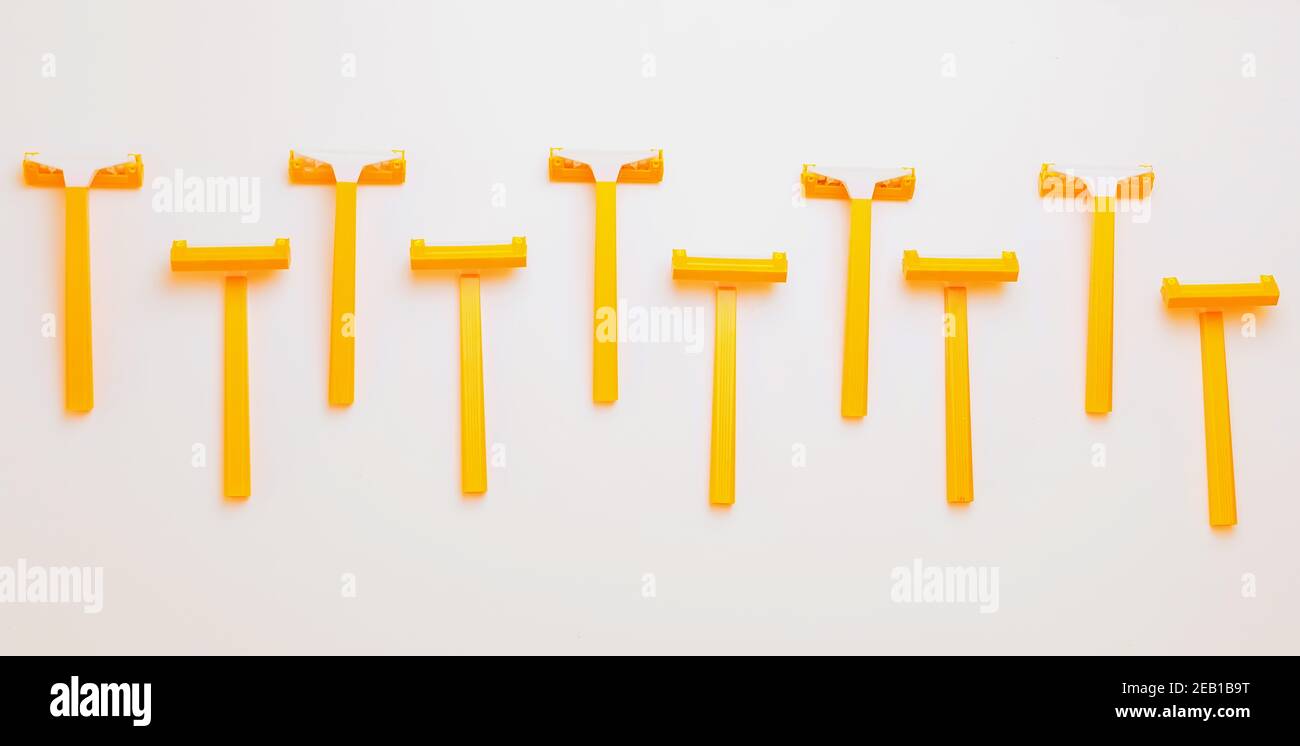Ten orange yellow shaving plastic simple razors in row on white Stock Photo