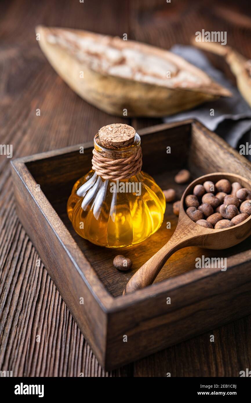 Baobab seed oil in glass bottle for healthy skin and hair on rustic wooden background Stock Photo