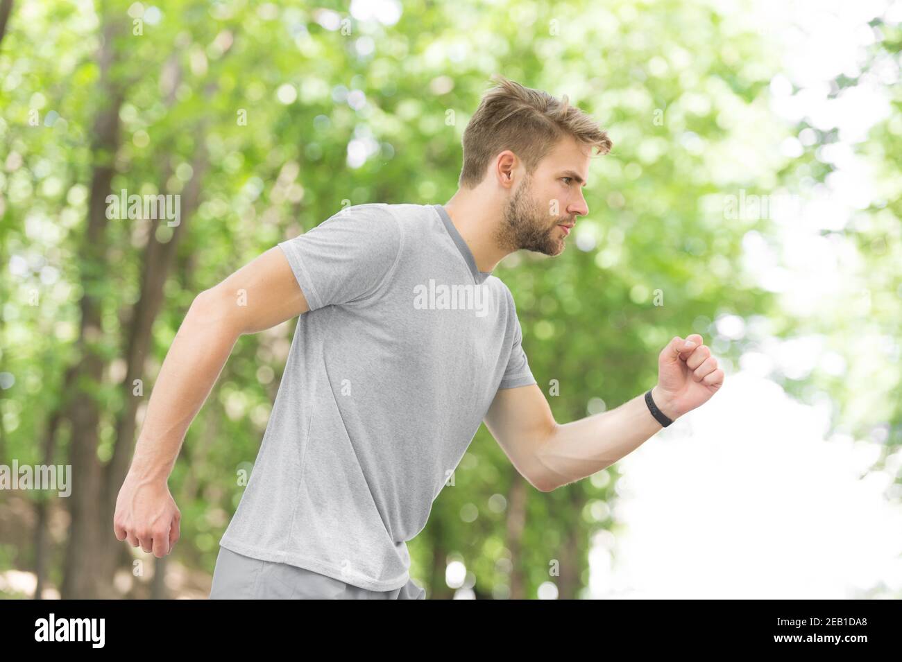 Moving to his goal. Man confident young running in park, side view. Sportsman ambitiously moves to achieve sport goal. Masculinity and sport achievements concept. Guy concentrated runs for his goal. Stock Photo