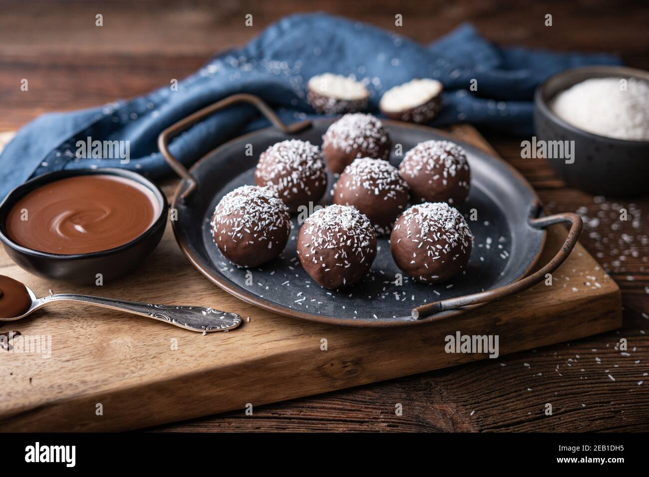 No bake delicious candy, sweet coconut balls dipped in chocolate on rustic wooden background Stock Photo
