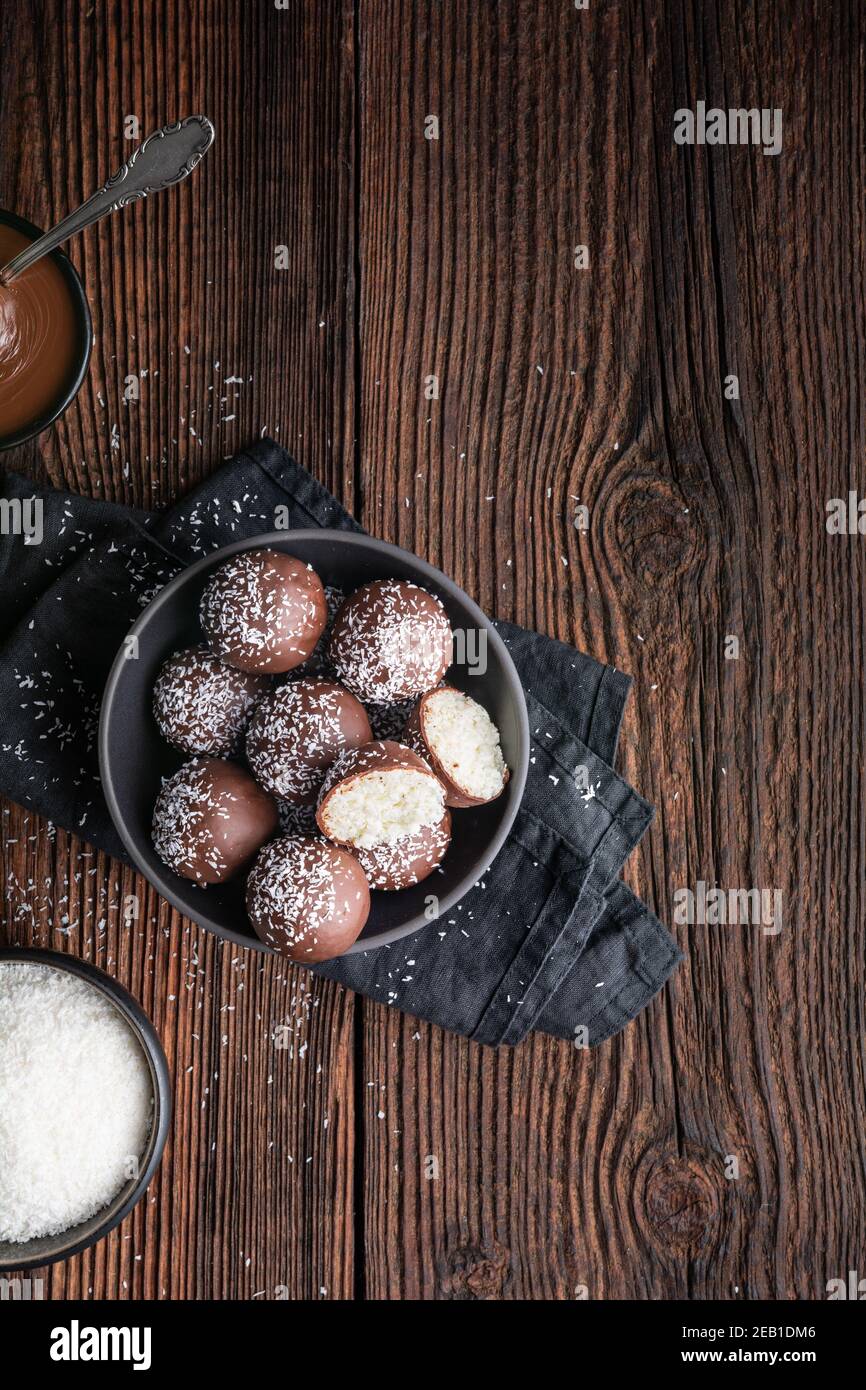 No bake delicious candy, sweet coconut balls dipped in chocolate on rustic wooden background with copy space Stock Photo