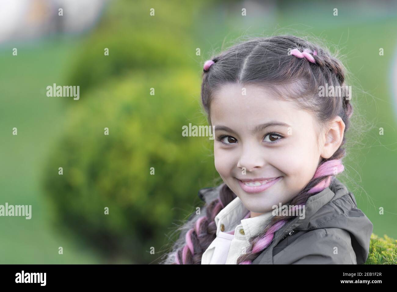Add bright detail. Little girl with cute braids nature background close up. Kanekalon strand in braids of cute child. Modern hairstyle concept. Girl with braided hair style with pink kanekalon Stock Photo - Add bright detail. Little girl with cute braids nature background close up. Kanekalon strand in braids of cute child. Modern hairstyle concept. Girl with braided hair style with pink kanekalon Stock Photo -