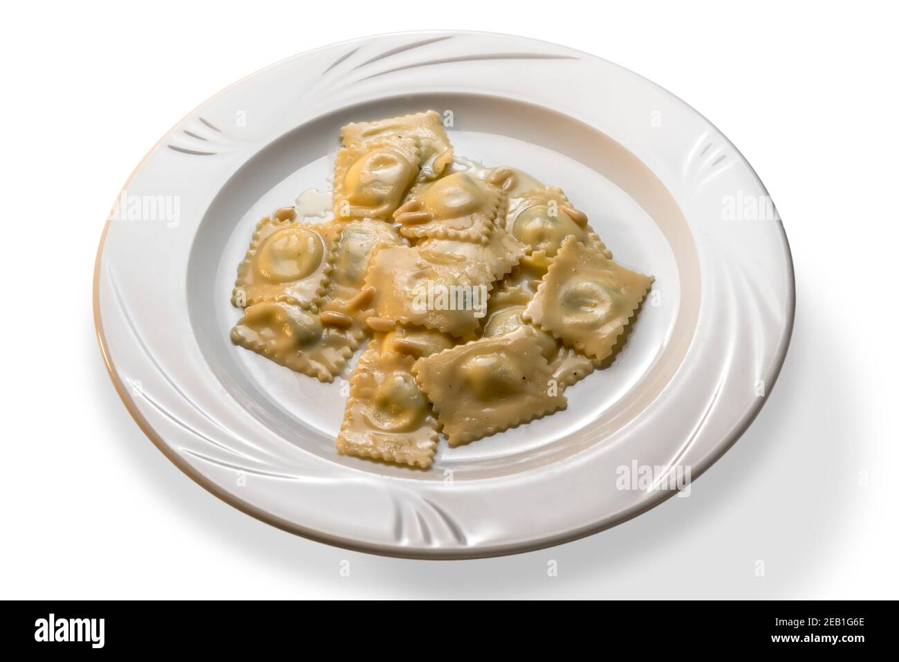 Ravioli - Italian stuffed egg pasta topped with pine nuts and butter sauce in white dish on white background Stock Photo