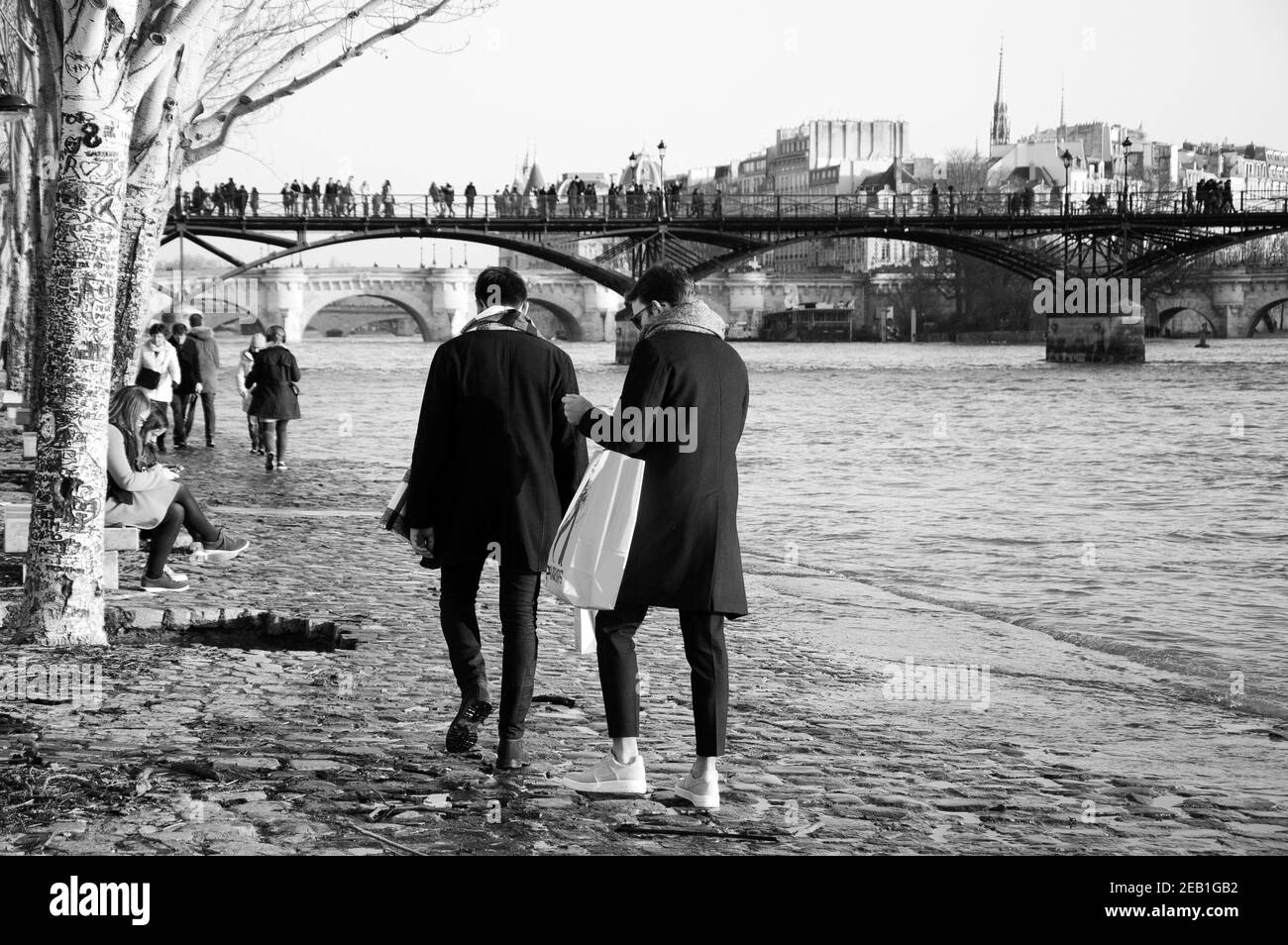 PARIS, FRANCE - JANUARY 14, 2018: Flood in Paris. Parisians and tourists promenade along wet embankment while high water in Seine river coming over qu Stock Photo