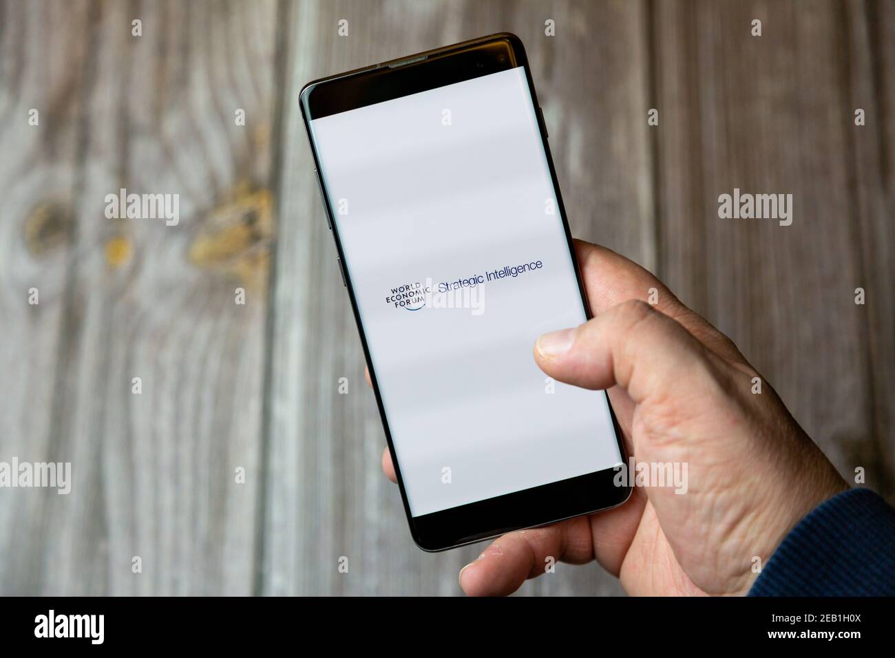 A mobile phone or cell phone being held by a hand with the World economic forum app open on screen Stock Photo
