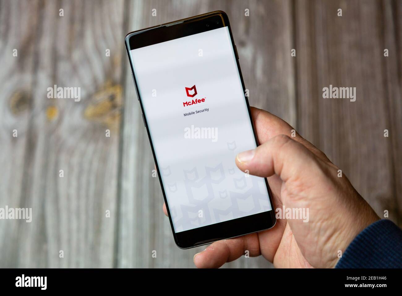 A mobile phone or cell phone being held by a hand with the McAfee Anti-Virus app open on screen Stock Photo