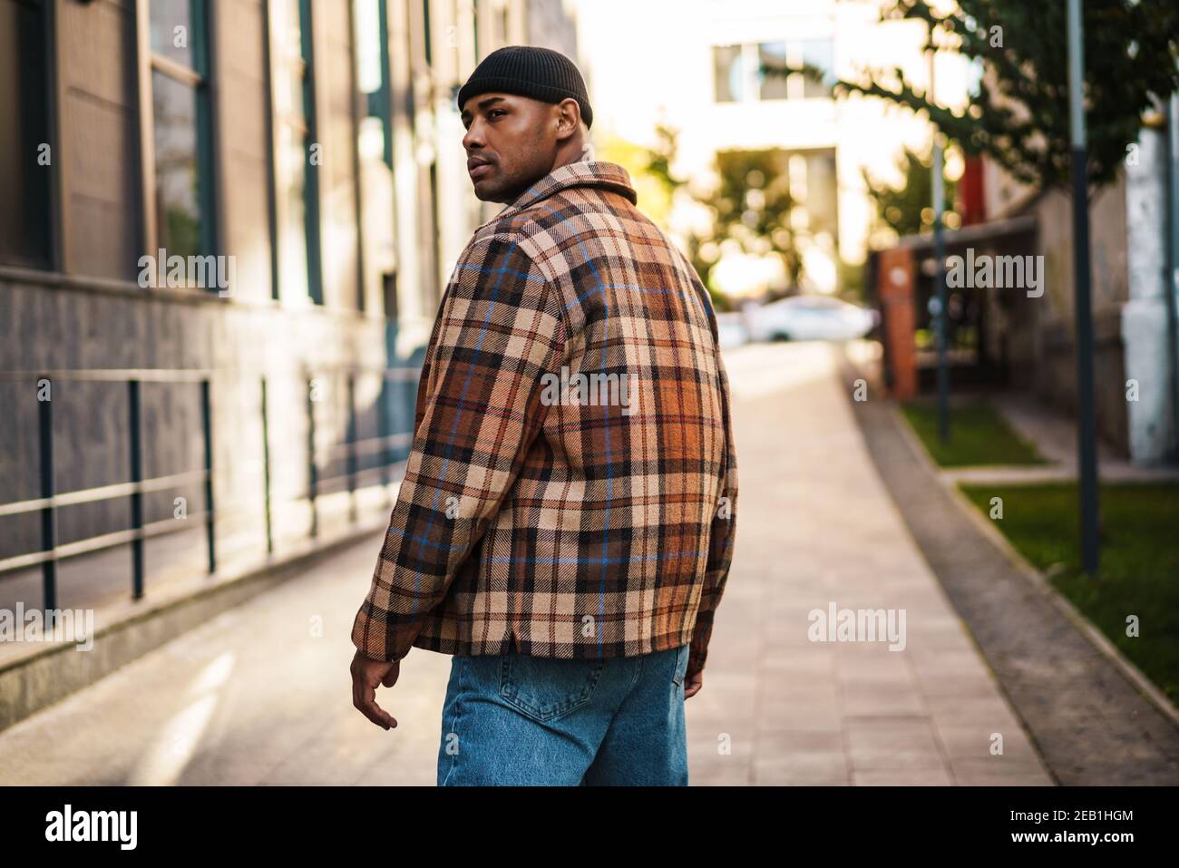 Confident stylish young afro american man walking on a street, back view Stock Photo