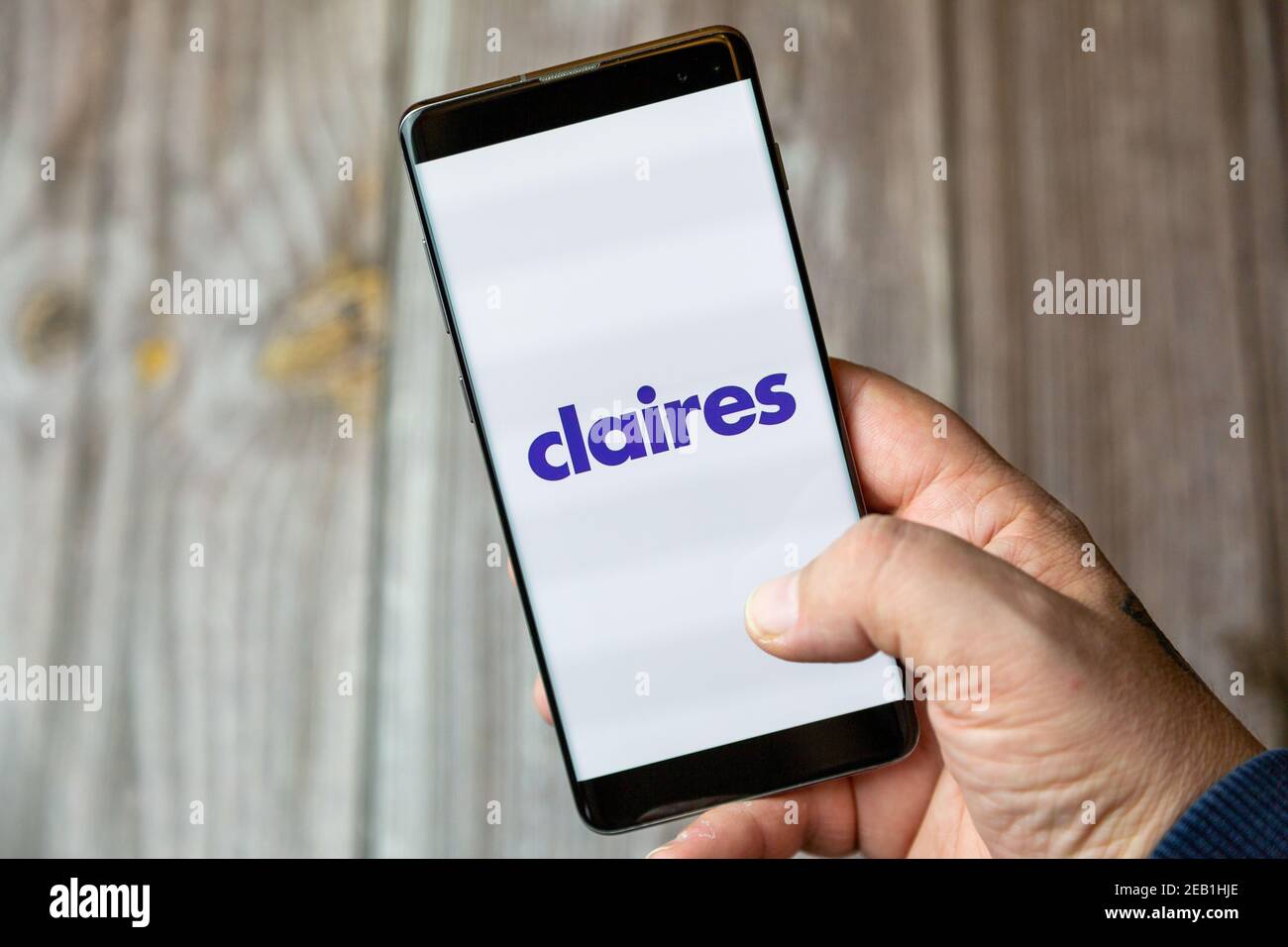 A mobile phone or cell phone being held by a hand with the Claires app