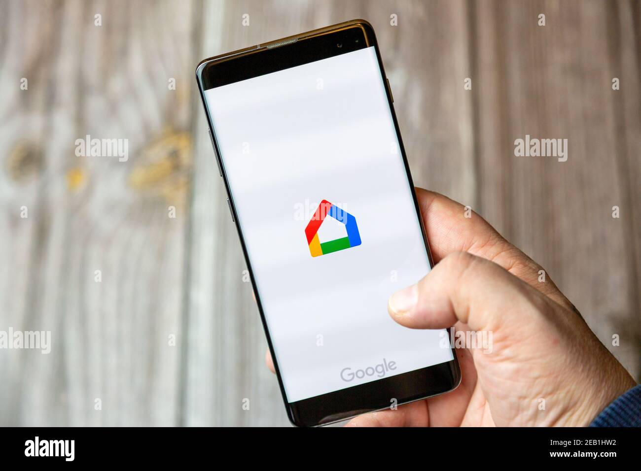 A mobile phone or cell phone being held by a hand with the Google Home app open on screen Stock Photo