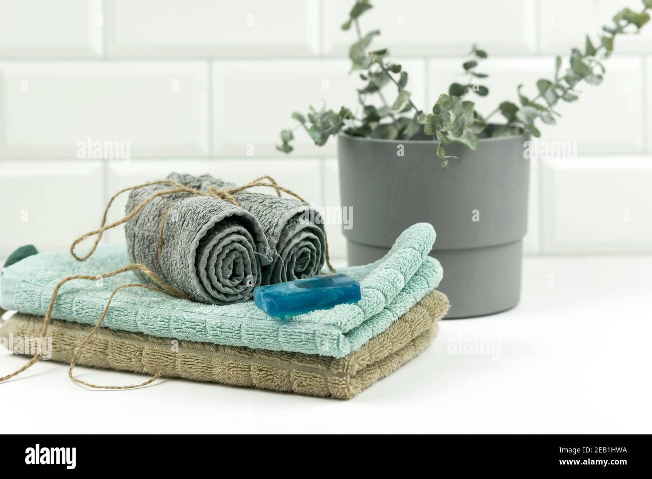 Cotton towels of neutral colour with a branch of eucalyptus on them lie on a table in a modern bathroom Stock Photo