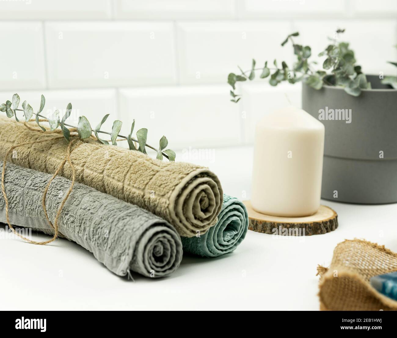 Cotton towels of neutral colour with a branch of eucalyptus on them lie on a table in a modern bathroom Stock Photo