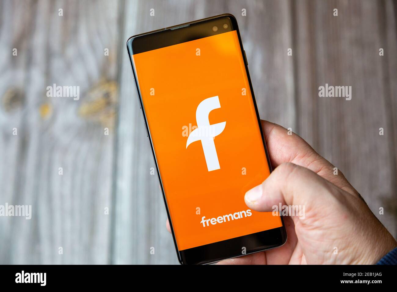 A mobile phone or cell phone being held by a hand with the Freemans shopping app open on screen Stock Photo