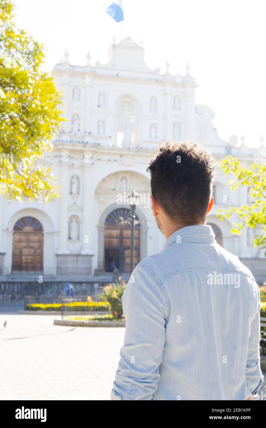 Hispanic young man standing in front of the San Jose cathedral in Antigua Guatemala - young tourist observing the church architecture in the colonial Stock Photo