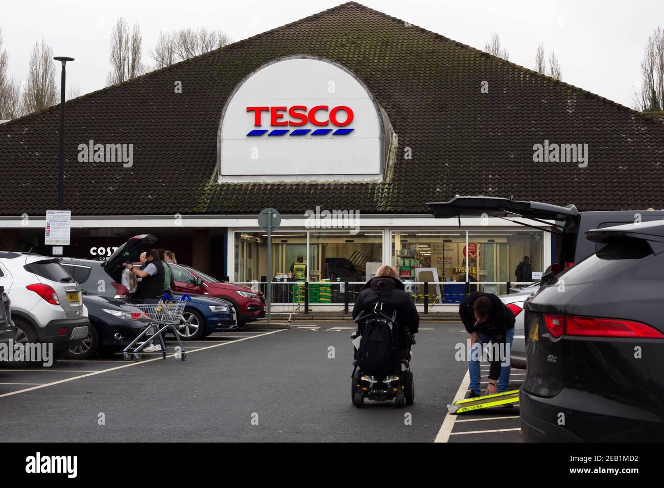 Shoppers in mobility scooter wearing face mask in Tesco supermarket car