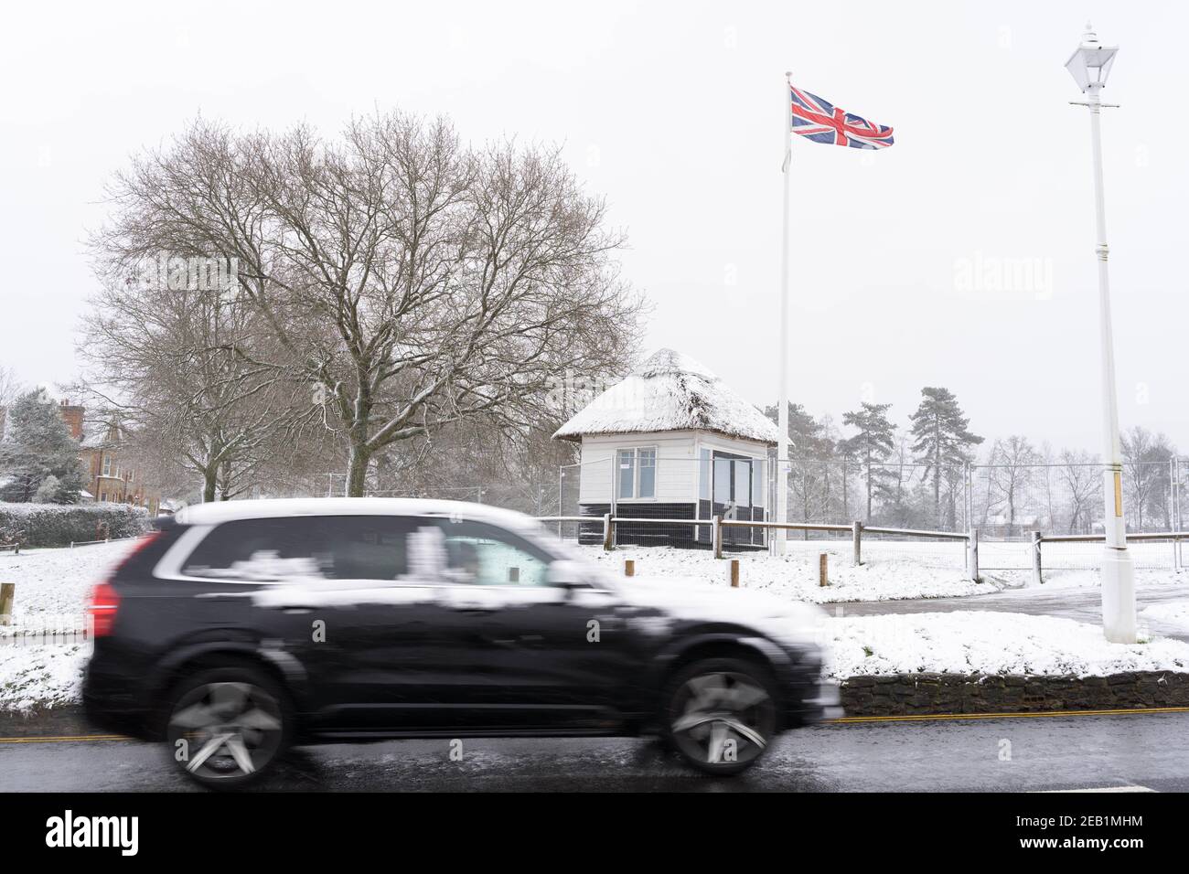 Union flag flying in the snow shower, black Suv car covered in snow Sevenoaks, Kent, England Stock Photo