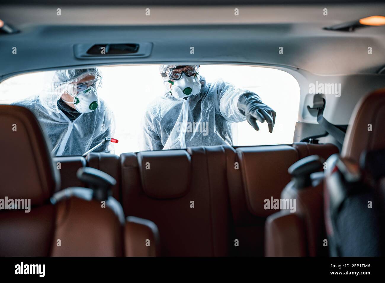 Disinfectant worker in protective masks and suits making disinfection of car seats Stock Photo