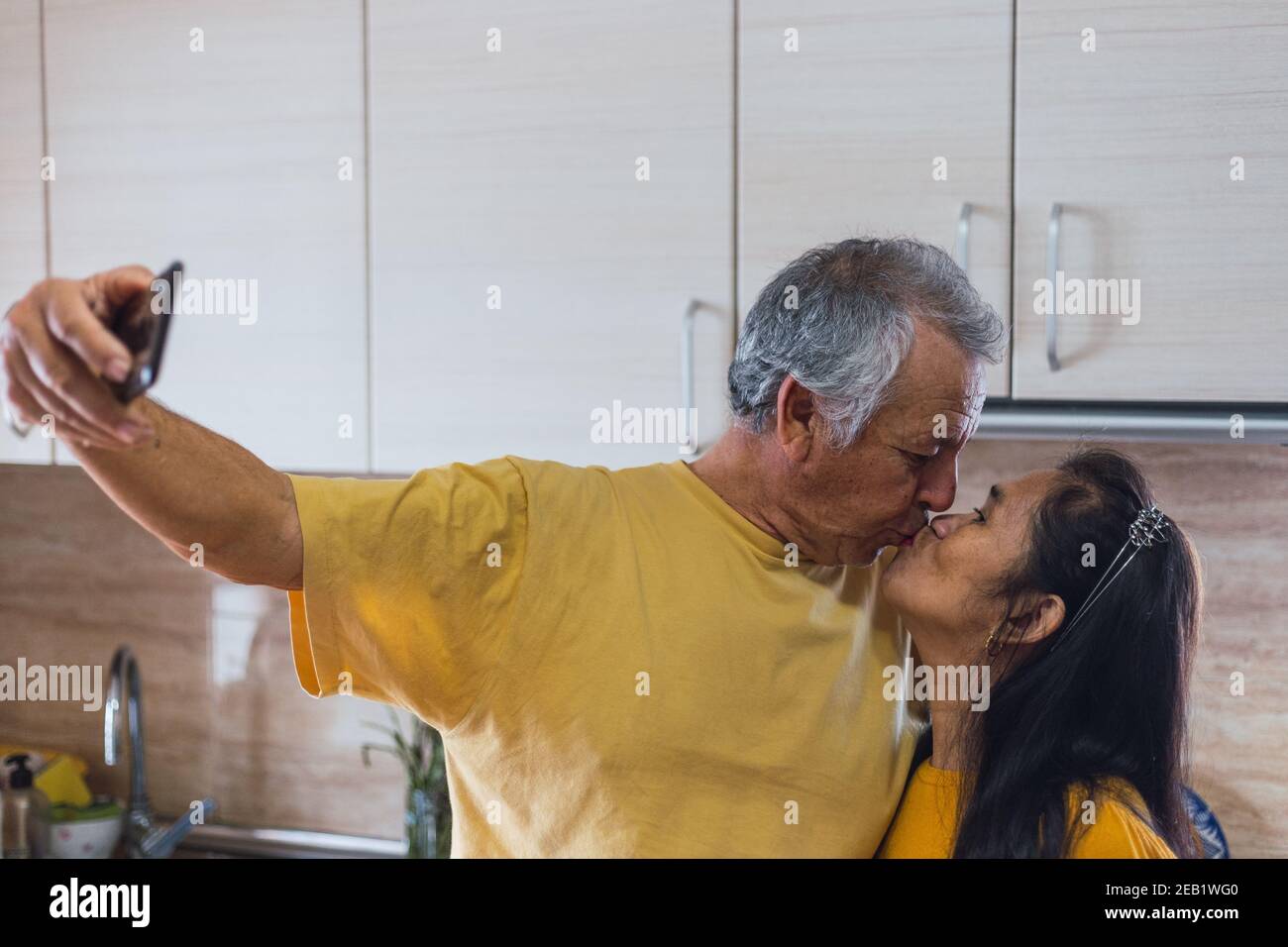 Old couple taking a selfie while kissing. Stock Photo