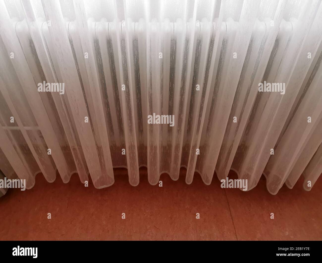 Transparent white curtain covering the radiator Stock Photo - Alamy