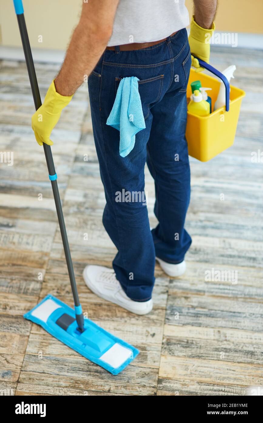 Quality cleaning. Professional male cleaner holding mop and plastic
