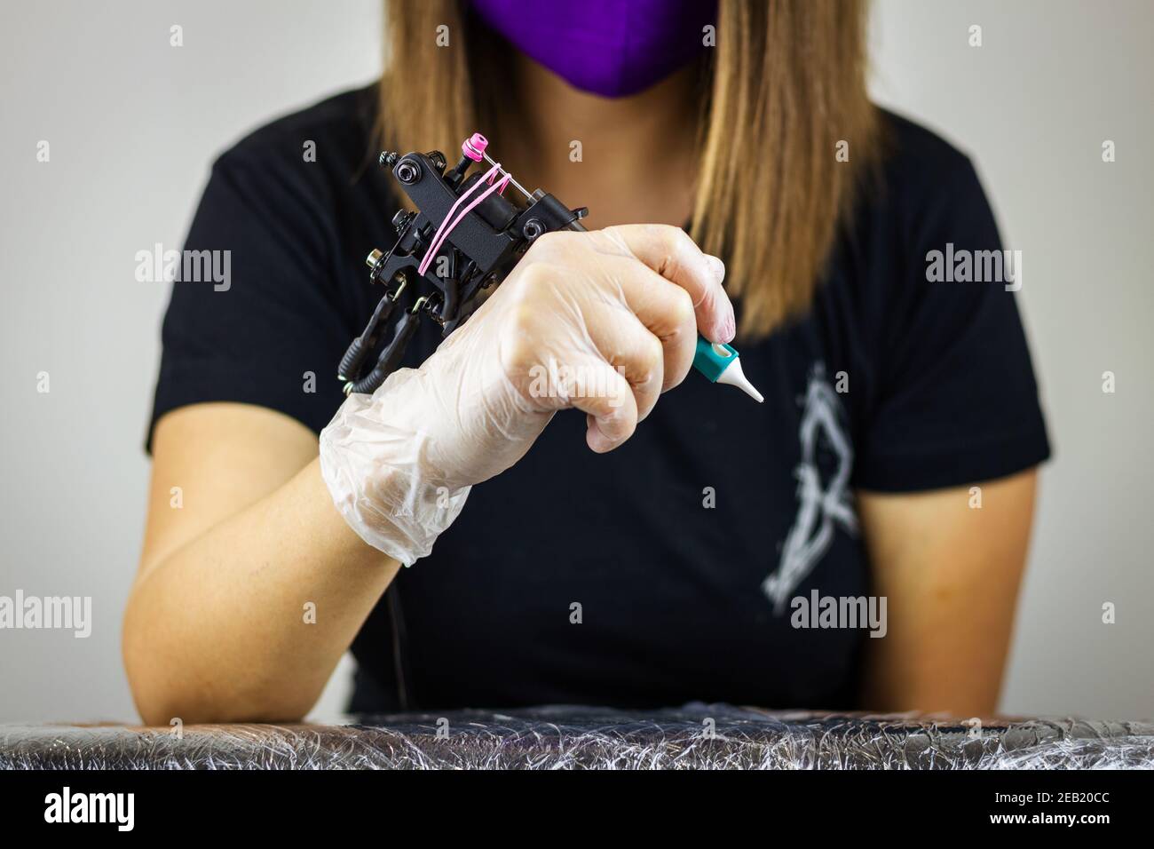Ready for tattooing. Woman with protective glove holding tattoo machine in studio. Creative occupation Stock Photo