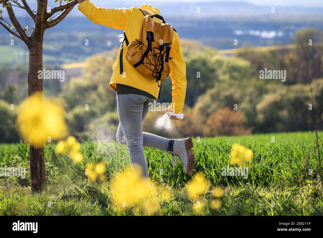 Hiking woman applying insect repellent against tick in nature. Prevention against mosquito