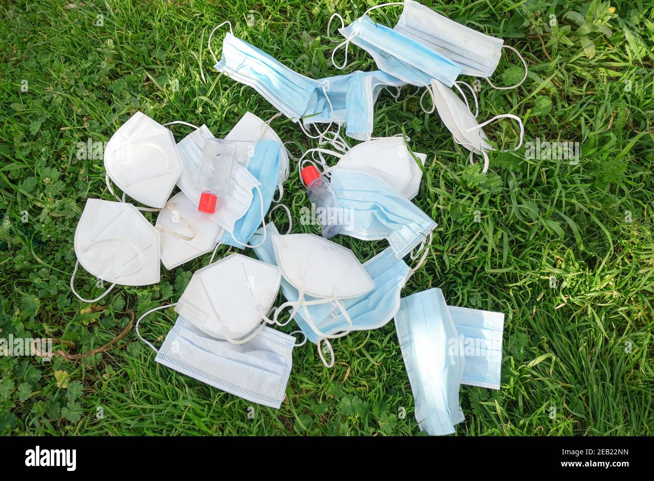 Used protective face mask and hand sanitizer bottle discarded on natural ecosystem,covid19 pandemic waste pollution Stock Photo
