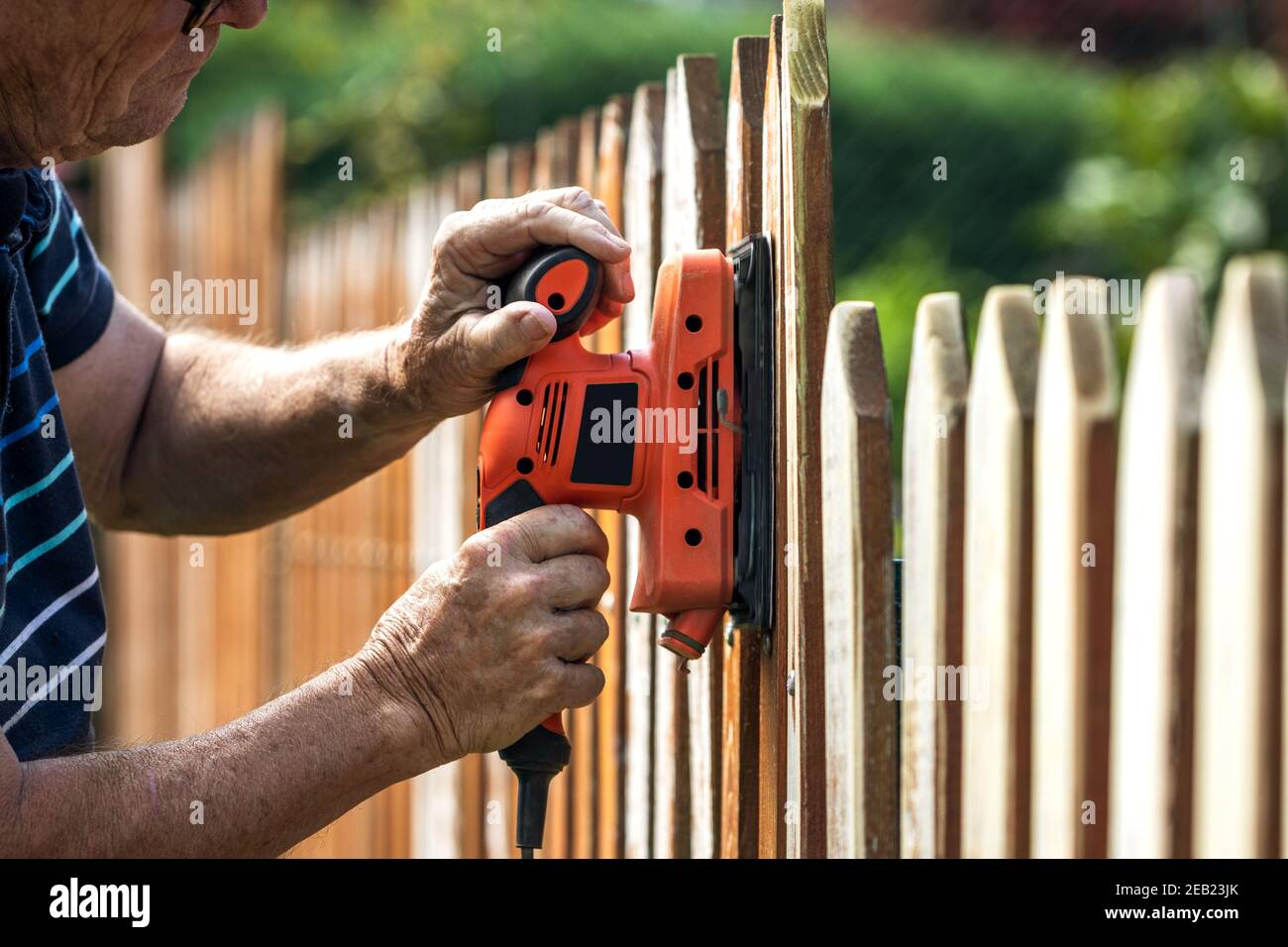 Sanding wood fence by sander. Senior 