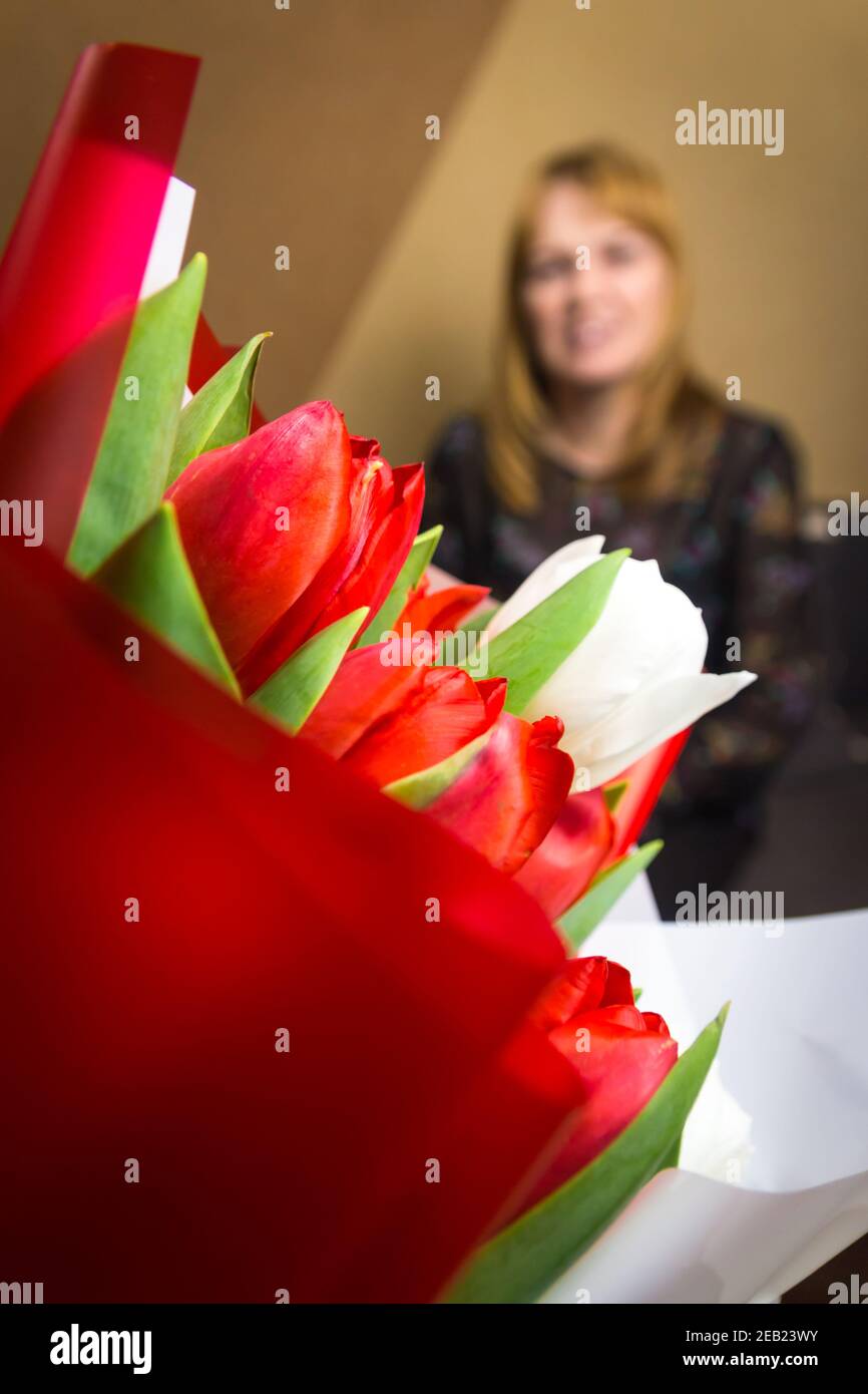 Flower woman. Bouquet of colorful tulips with blurred woman on background Happy Mother's Day concept. Women's day. Vertical. 8 march. Focus on Stock Photo